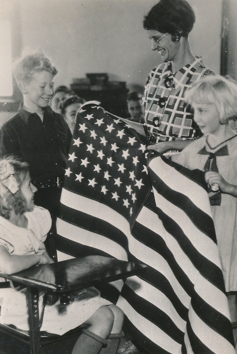 Teacher and students are both very pleased with an American flag sewn by WPA workers in Grand Rapids, Michigan. Photo courtesy of the National Archives (ca. 1935-1943).